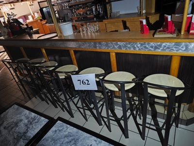 un bar avec de nombreux tabourets et une enseigne accrochée au comptoir