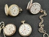 many different types of pocket watches on a black cloth