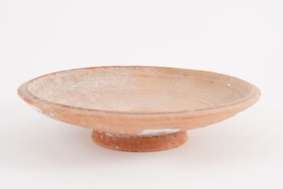 a small bowl on a stand on a white surface