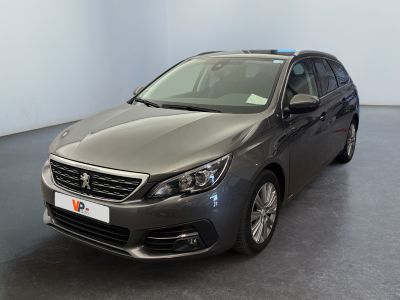La voiture grise est garée dans une grande pièce au sol noir.