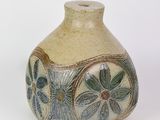 un petit vase posé sur une surface blanche