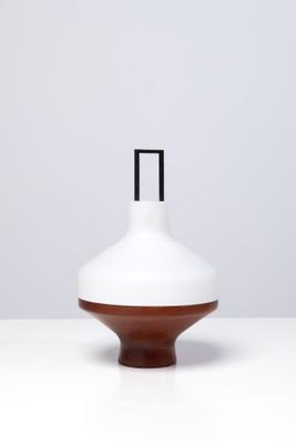 un vase blanc et marron posé sur une table blanche