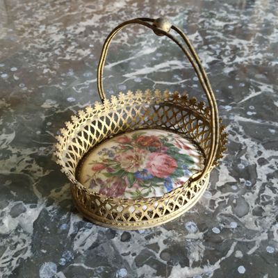 panier en métal doré orné d'un motif floral, posé sur une surface en marbre