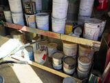 many buckets of paint sitting on a shelf in a garage