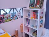 a room with a desk, bookshelf, and pictures on the wall