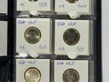 several coins are in a black case on a white surface