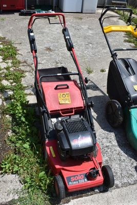 two lawn mowers sitting next to each other on the side of the road