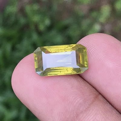 quelqu'un tient dans sa main une pierre précieuse jaune et blanche