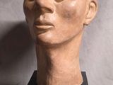 sculpture représentant une tête d'homme posée sur un socle noir