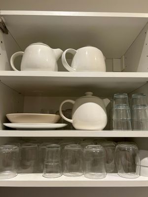 une étagère blanche sur laquelle sont posés de nombreux plats et tasses