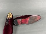 burgundy velvet shoes with gold heel and laces on a grey surface