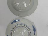 two plates with blue designs on them on a white surface