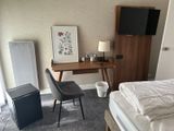 a bedroom with a bed, desk, and television in it