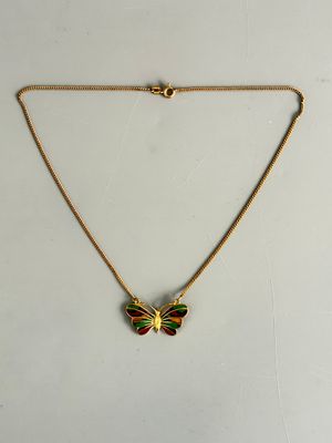 un collier en or orné d'un papillon vert et rouge