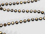 a black and gold beaded necklace on a white surface