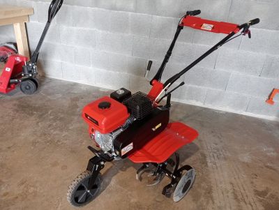 a small red tiller sitting in a garage