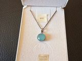 an open box containing a necklace with a blue stone on it