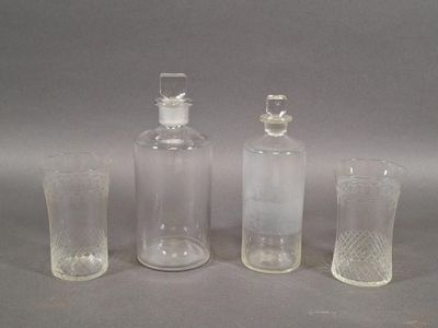 three clear glass bottles and a shot glass sitting on a table