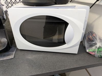 a microwave sitting on a counter with a bag of food in front of it