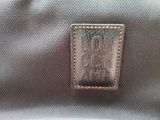 the back of a gray bag with a leather patch on it