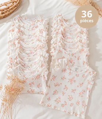 a white top with pink flowers and a straw hat on a bed