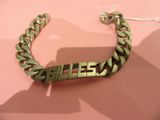 a metal bracelet with a name on it on a pink surface