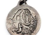 a close up of a silver medal with the image of the virgin mary