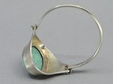 a close up of a silver ring with a green stone inside of it