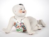 une figurine en porcelaine représentant un bébé allongé par terre