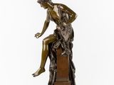 a bronze statue of a woman sitting on a rock