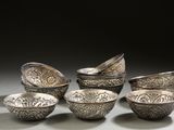 several silver bowls and spoons are lined up on a table