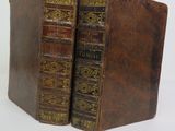 two old books sitting on top of each other on a table