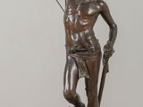 bronze statue of a man holding a sword on a wooden table