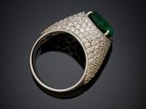 a close up of a ring with a green stone surrounded by diamonds