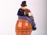 a figurine of a man sitting on top of a barrel