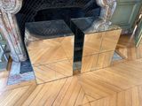 deux tables recouvertes d'un tissu à motifs de miroirs, posées à même le sol devant une cheminée