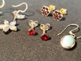 several pairs of earrings are displayed on a black surface