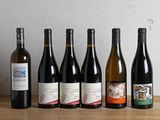 several bottles of wine are lined up on a wooden table