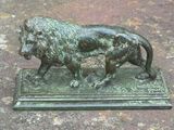 statue en bronze représentant un lion posée sur un socle au sol