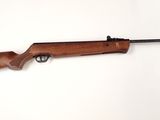 un fusil posé sur une surface blanche, avec une crosse noire