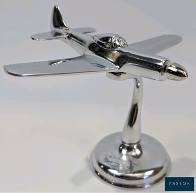 une maquette en argent représentant un petit avion, posée sur un socle