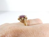 a woman ' s hand holding a ring with a ruby stone on it