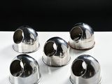 four silver metal objects sitting on top of a white table