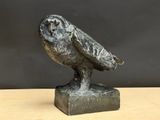 une photo représentant une statue de chouette posée sur une table en bois