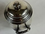 an antique silver plated sugar dish with a lid on a white table