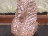 une statue en pierre représentant un pharaon assis sur une table noire
