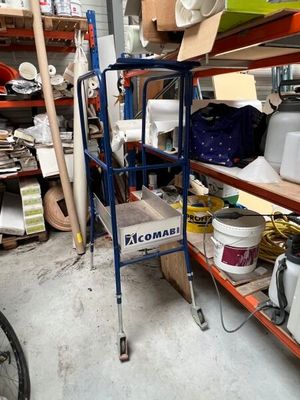 a blue cart in the middle of a room filled with items
