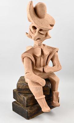 statue of a man with a hat sitting on a wooden block