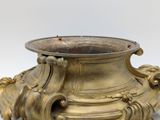 a gold vase that is sitting on a white surface