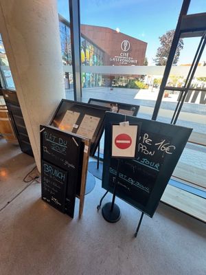 un panneau en ardoise placé devant une vitrine, sur lequel figure un menu